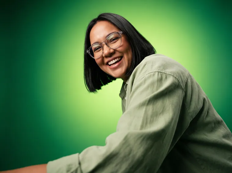 Mulher de cabelo bob e óculos rindo sobre fundo verde vivo